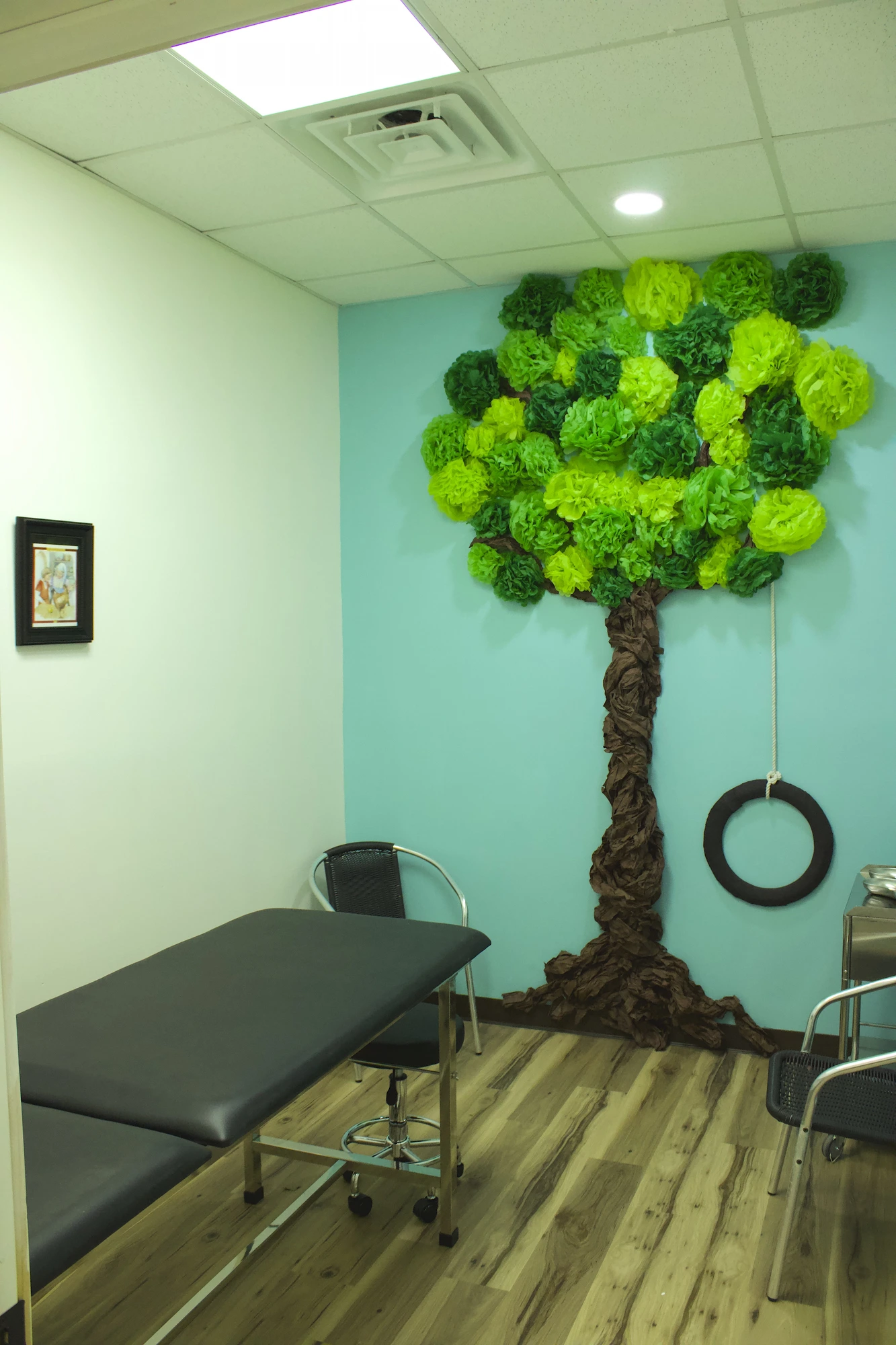 A Treehouse exam room with a handcrafted tree and tire swing on the wall